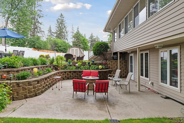 view of patio featuring fence, a fire pit, an outdoor structure, and a shed