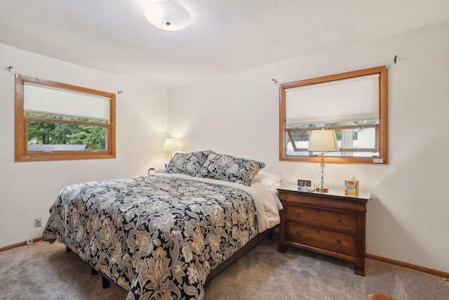 carpeted bedroom featuring a textured ceiling and baseboards