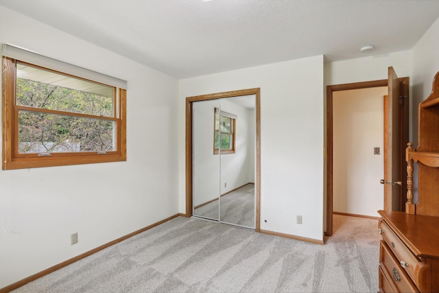 unfurnished bedroom featuring a closet, light carpet, and baseboards