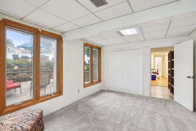 unfurnished bedroom with a drop ceiling, carpet flooring, visible vents, a closet, and tile patterned floors