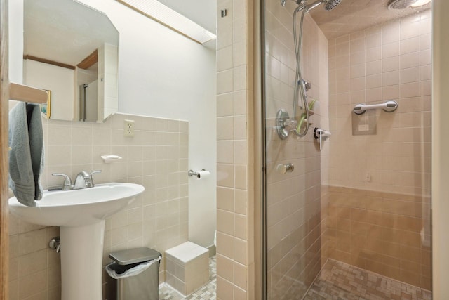 full bathroom with a sink, a shower stall, and tile walls