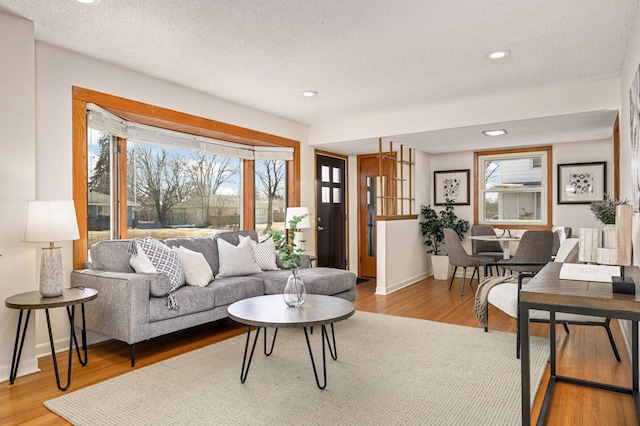 living area with recessed lighting, wood finished floors, baseboards, and a textured ceiling