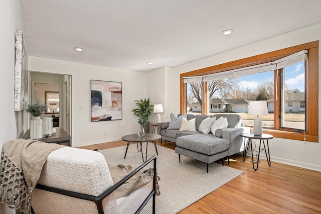 living area with recessed lighting, baseboards, light wood-style floors, and a textured ceiling