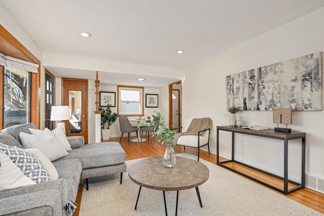 living room featuring recessed lighting, wood finished floors, visible vents, and a textured ceiling