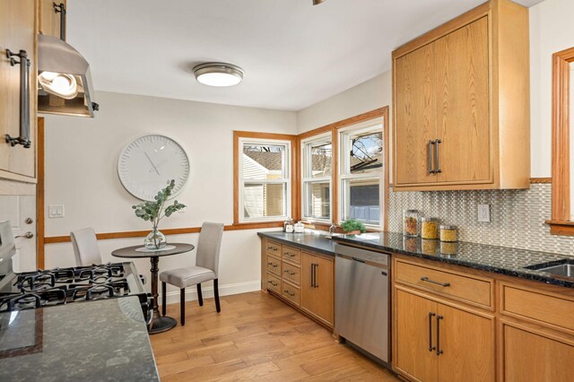 kitchen featuring dark stone countertops, stainless steel dishwasher, range with gas cooktop, light wood-style floors, and decorative backsplash