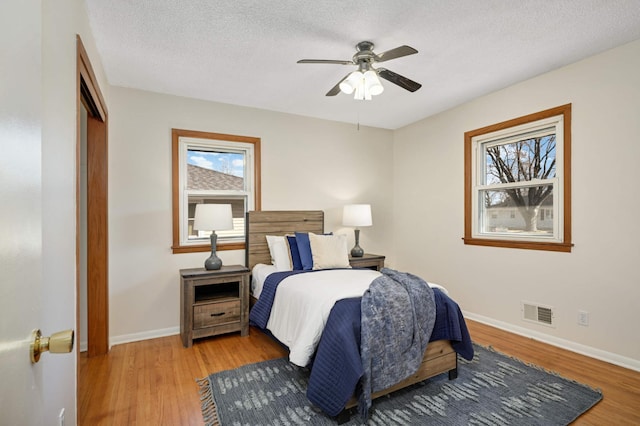 bedroom featuring light wood-type flooring, multiple windows, and visible vents