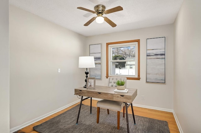 office area with ceiling fan, a textured ceiling, light wood-type flooring, and baseboards