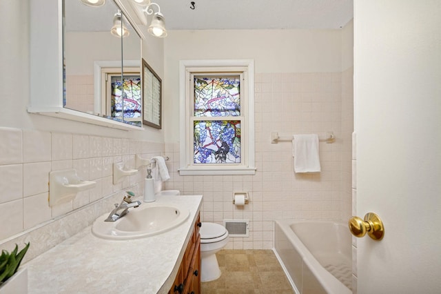 bathroom with vanity, visible vents, a bathing tub, tile walls, and toilet