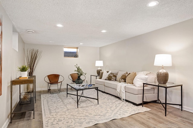 living area featuring light wood-style floors, baseboards, and a textured ceiling