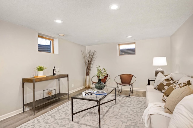 living room featuring recessed lighting, wood finished floors, baseboards, and a textured ceiling