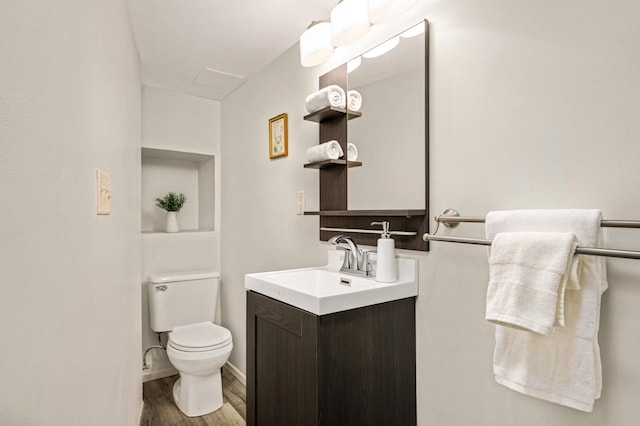 bathroom featuring toilet, vanity, baseboards, and wood finished floors