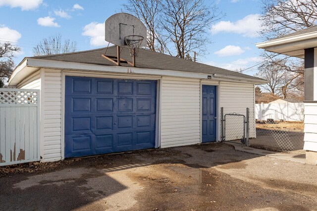 detached garage featuring a gate, driveway, and fence