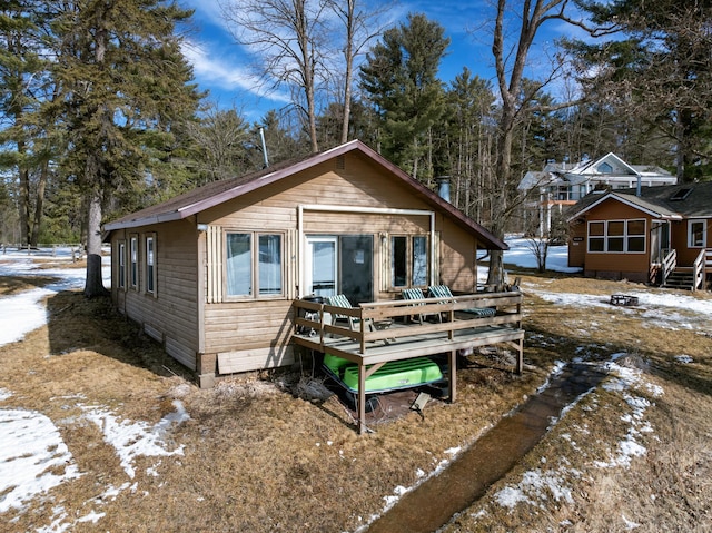 snow covered house featuring a wooden deck