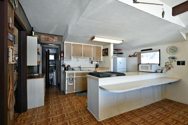 kitchen with white appliances, a peninsula, light countertops, a textured ceiling, and a sink