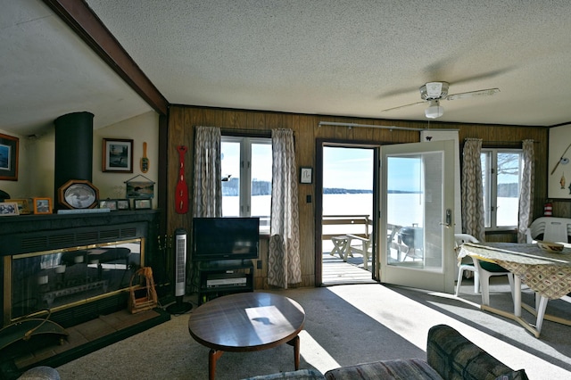 living room with carpet floors, wooden walls, a textured ceiling, and a glass covered fireplace