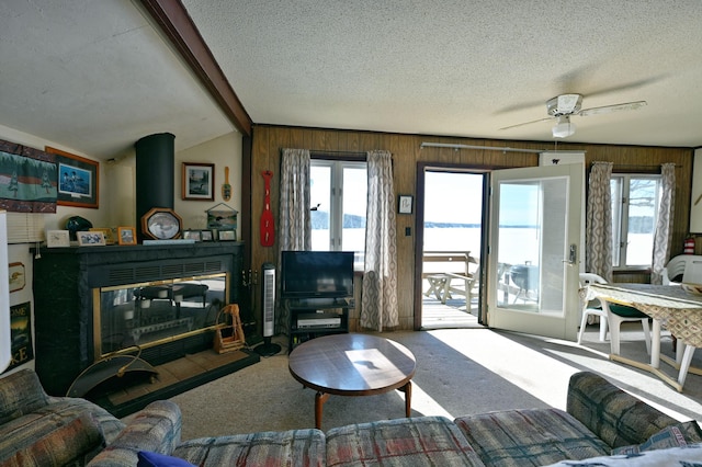 living area with plenty of natural light, a textured ceiling, carpet, and vaulted ceiling with beams