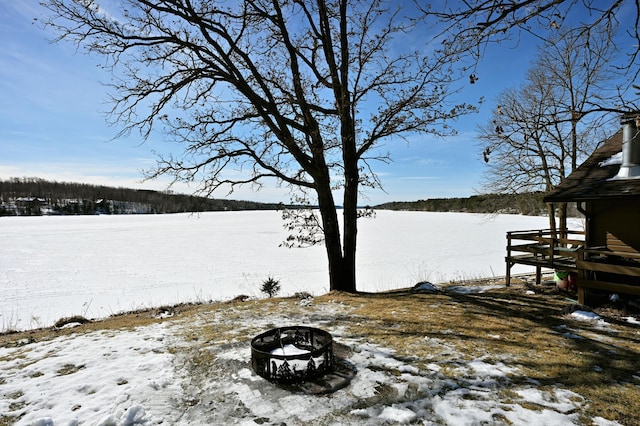 snowy yard with a fire pit and a water view