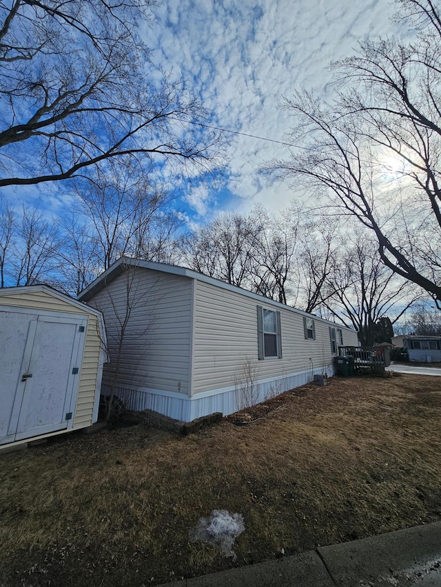 view of side of home featuring an outbuilding, a lawn, and a storage shed