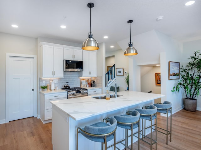 kitchen with decorative backsplash, a breakfast bar, stainless steel appliances, light wood-type flooring, and a sink