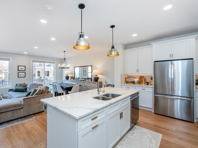 kitchen with stainless steel appliances, light wood-type flooring, open floor plan, and a sink