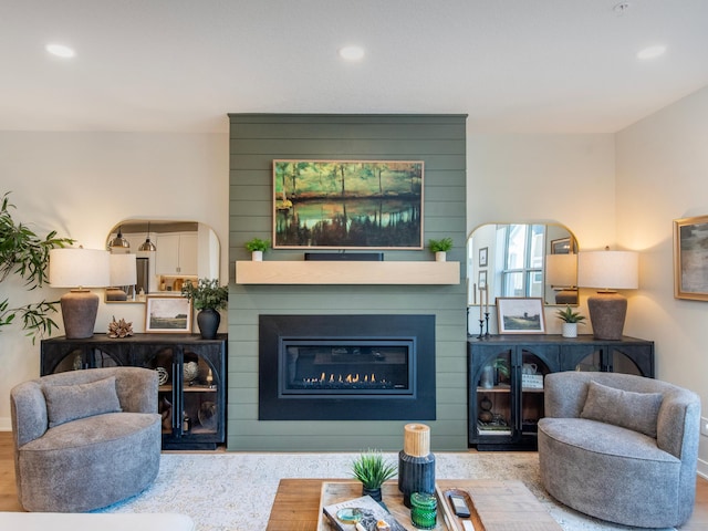 living room featuring recessed lighting, a large fireplace, and wood finished floors