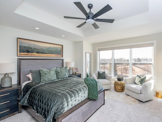 bedroom featuring a ceiling fan, a raised ceiling, and carpet flooring