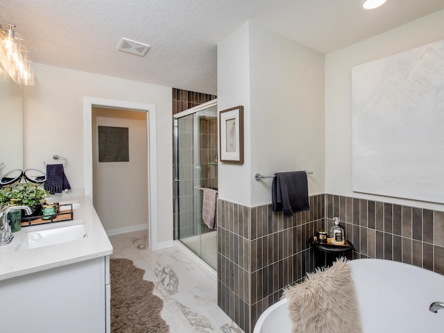 full bath with a textured ceiling, visible vents, marble finish floor, a soaking tub, and a shower stall