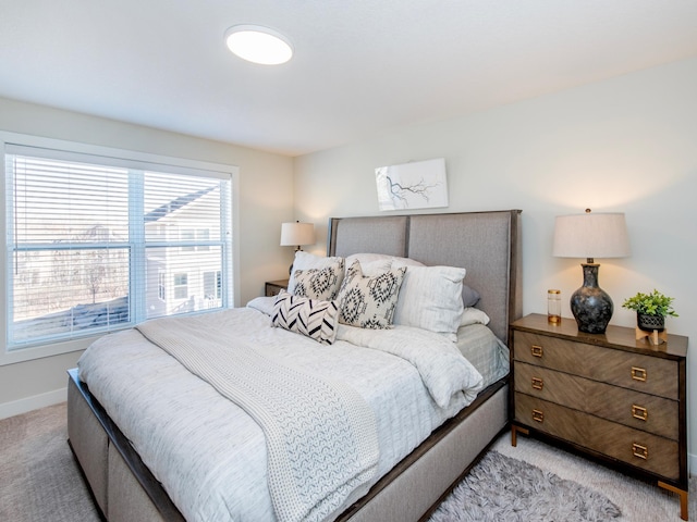 bedroom with baseboards and light colored carpet