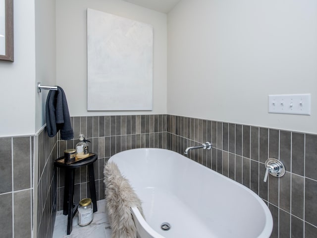 full bathroom with wainscoting, a freestanding bath, and tile walls