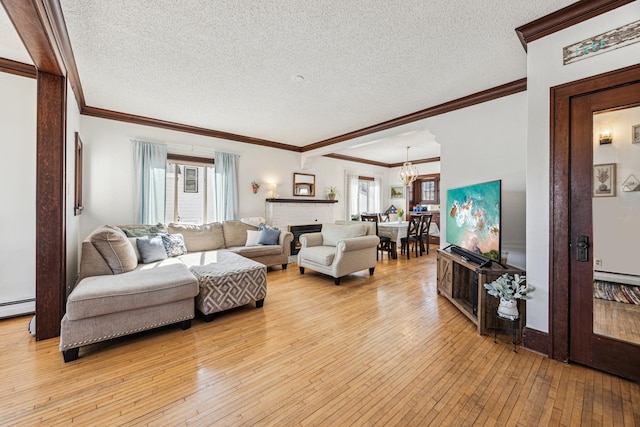 living area featuring light wood finished floors, a chandelier, a textured ceiling, and crown molding