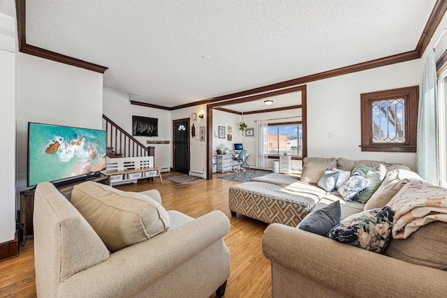 living room with stairway, wood finished floors, baseboards, ornamental molding, and a textured ceiling