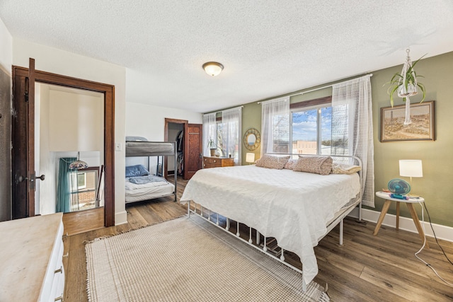 bedroom with wood finished floors, baseboards, and a textured ceiling