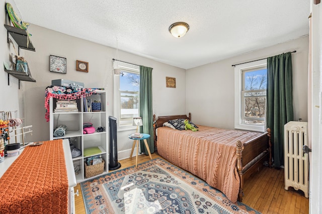 bedroom with radiator, hardwood / wood-style floors, and a textured ceiling