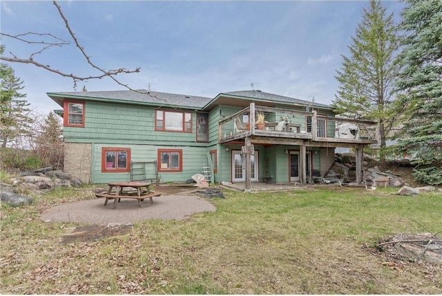 rear view of house with a yard, a wooden deck, and a patio