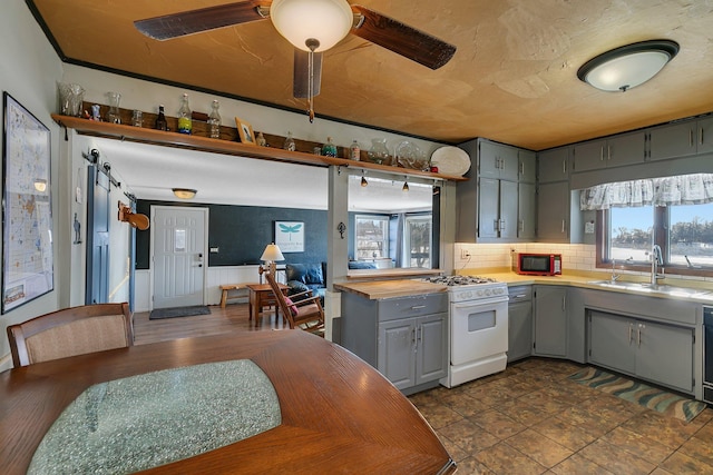 kitchen with tasteful backsplash, white gas range oven, gray cabinets, light countertops, and a sink