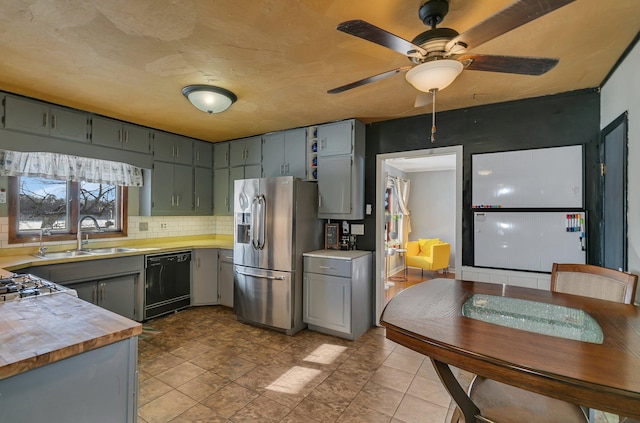 kitchen with gray cabinets, backsplash, a sink, stainless steel fridge, and dishwasher