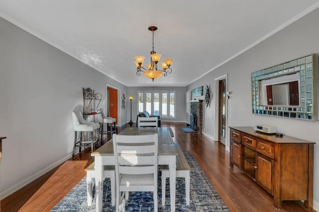 dining area featuring baseboards, dark wood finished floors, a notable chandelier, and ornamental molding