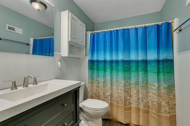 bathroom featuring a wainscoted wall, toilet, vanity, and visible vents