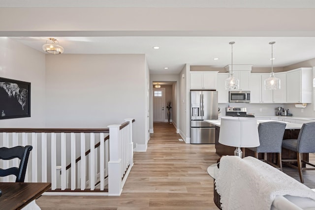 kitchen featuring stainless steel appliances, light wood-type flooring, light countertops, and white cabinetry