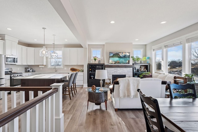 living area featuring light wood-type flooring, recessed lighting, and a stone fireplace