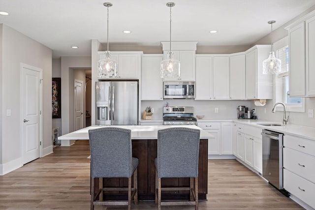 kitchen featuring appliances with stainless steel finishes, white cabinetry, a sink, and light wood finished floors