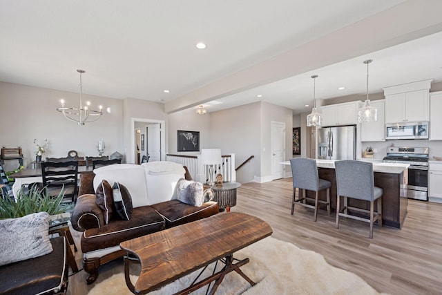 living room with light wood finished floors, an inviting chandelier, and recessed lighting