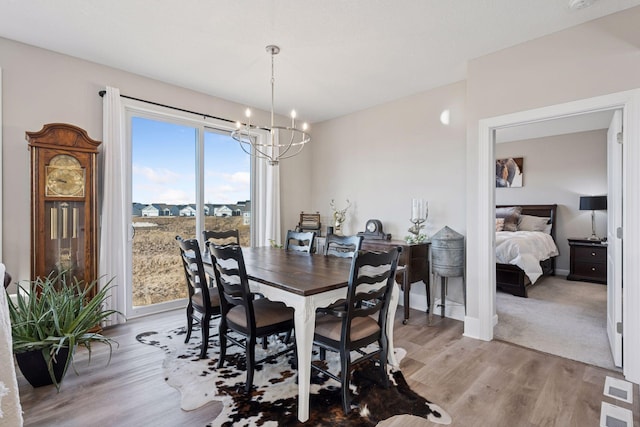 dining area featuring baseboards, light wood finished floors, visible vents, and an inviting chandelier