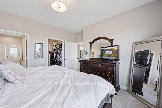 bedroom with connected bathroom, light colored carpet, baseboards, a spacious closet, and a closet