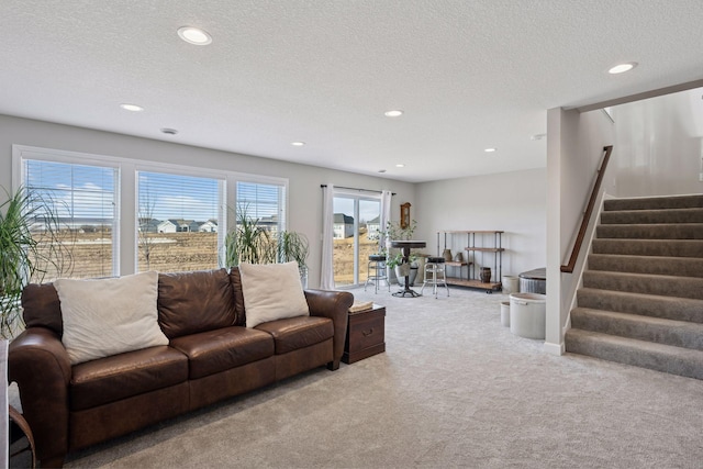 living room featuring recessed lighting, stairway, a textured ceiling, and light colored carpet