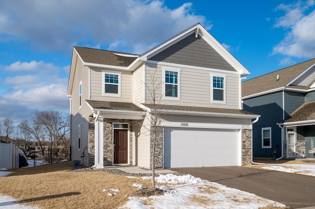 view of front facade with driveway, stone siding, an attached garage, and roof with shingles