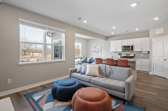 living room with recessed lighting, dark wood finished floors, visible vents, and baseboards