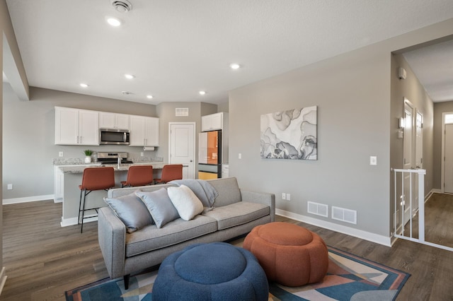 living room with visible vents, baseboards, dark wood-type flooring, and recessed lighting