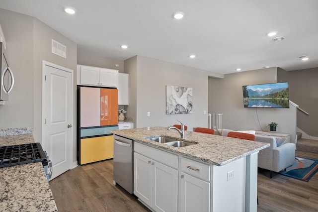 kitchen with a sink, visible vents, open floor plan, appliances with stainless steel finishes, and dark wood-style floors