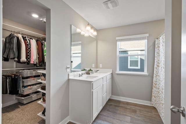 bathroom featuring wood finished floors, a sink, visible vents, and baseboards